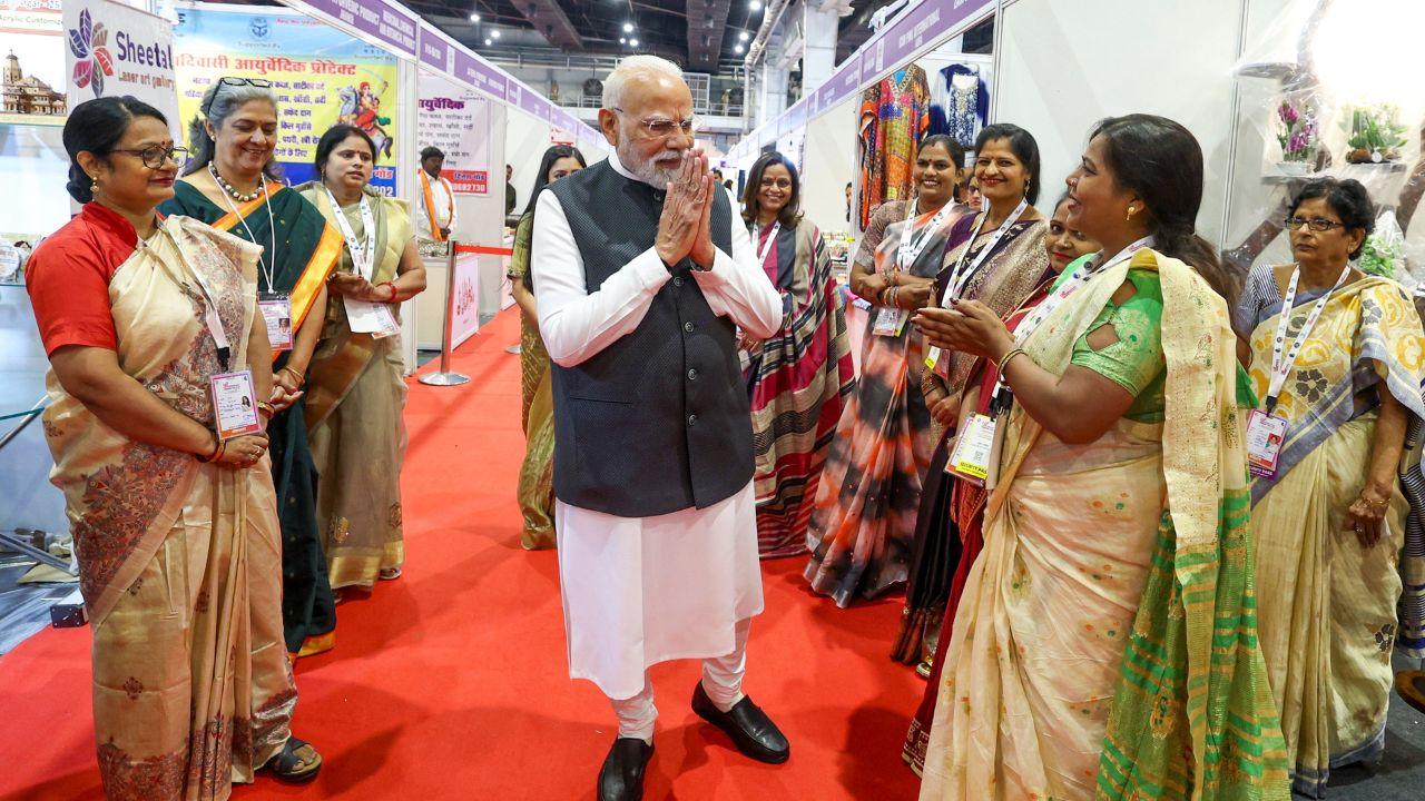 Prime Minister Narendra Modi interacts with a woman at a stall during the inauguration of the Uttar Pradesh International Trade Show 2025 in Greater Noida